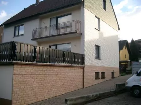 Frontansicht einer neu verkleideten Fassade eines Hauses in Steinoptik mit weißen und Lehmfarbenen Steinen