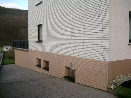 Seitenansicht einer neu verkleideten Fassade eines Hauses in Steinoptik mit weißen und Lehmfarbenen Steinen