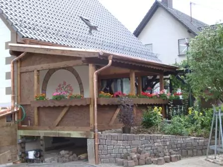 Seitenansicht einer fertig gestellte Terrassenüberdachung aus Holz mit Vorgarten